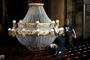 "Staff adjusts the chandelier prior to showtime."  Photo by Tom Jones.